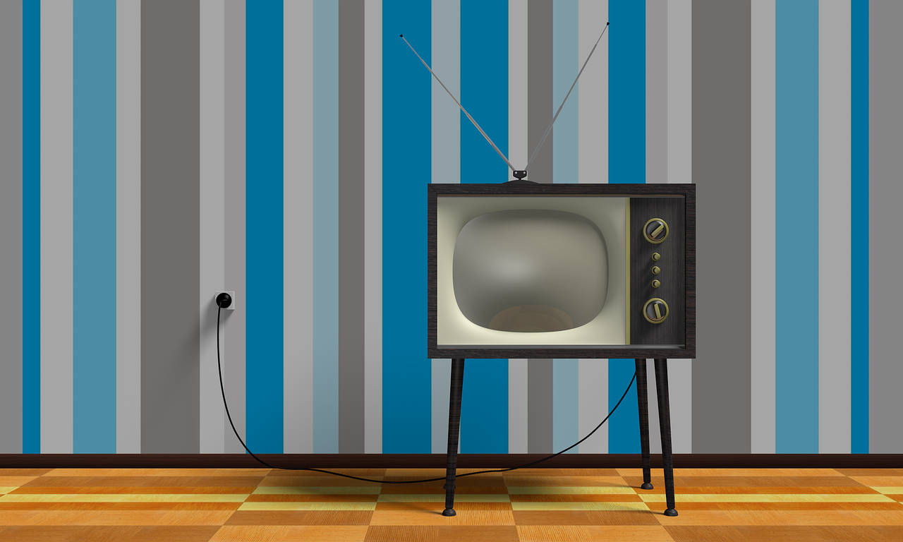 Old TV with a rainbow wallpaper behind it.