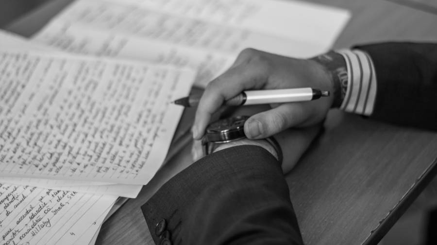 Papers on a desk. Man in suit holding a fountain pen.