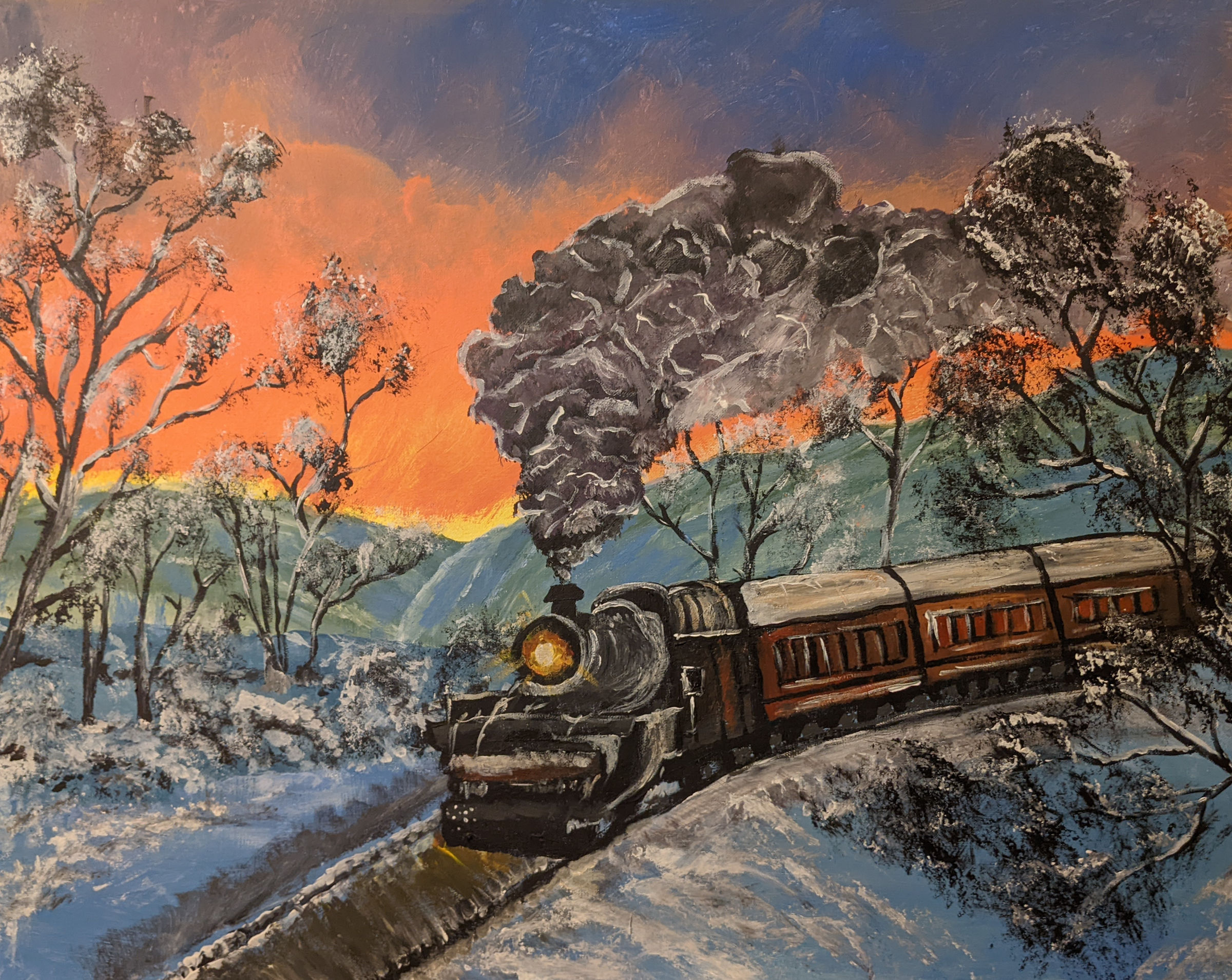 Train traveling down the tracks in the snow. Trees surround it in the foreground and background. Snowy mountains are in the distance, and the sky is a bright orange.