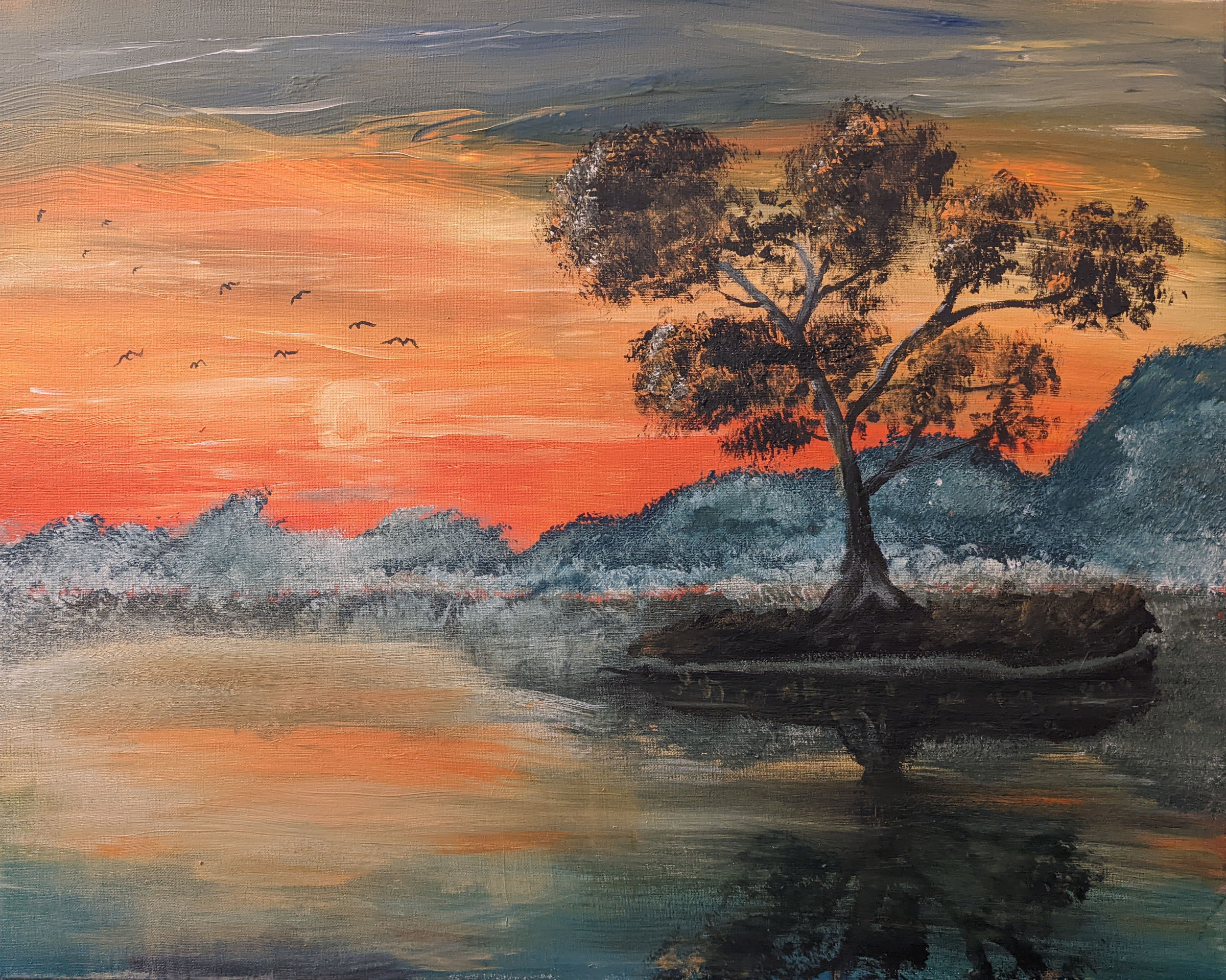 Setting sun in an orange sky over a lake. Several birds are flying through the sunlight, and a tree blows in the wind on a tiny island in the lake.