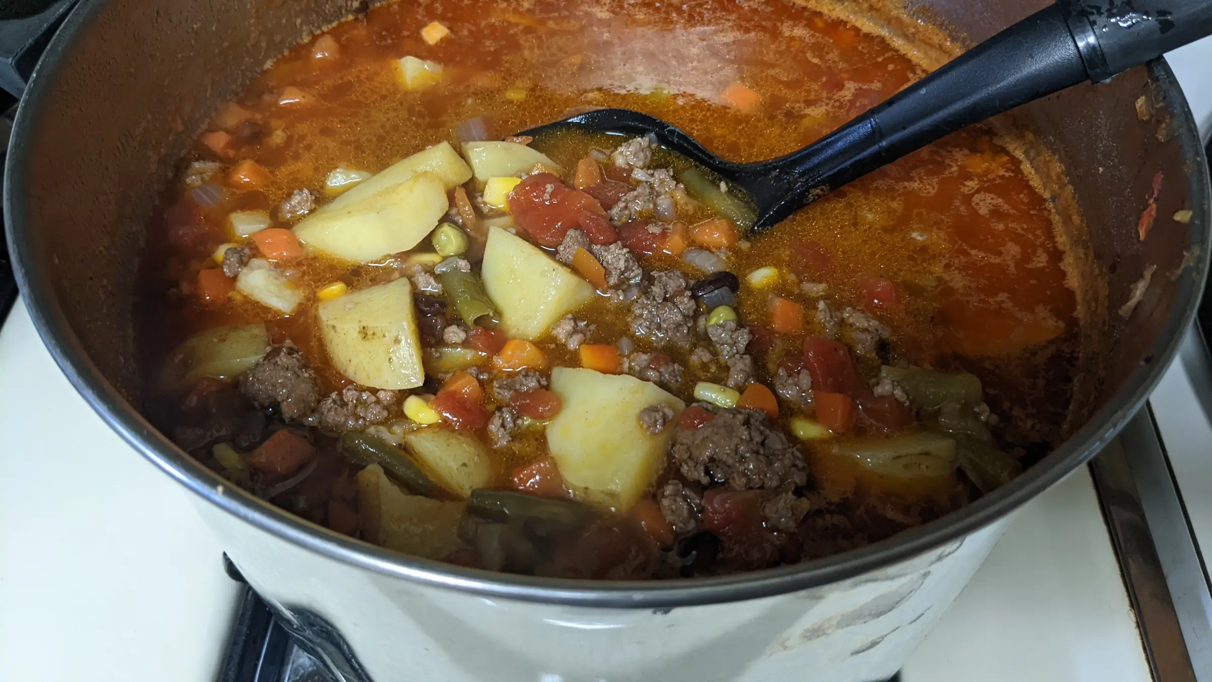 Large pot on a stove with hamburger soup.