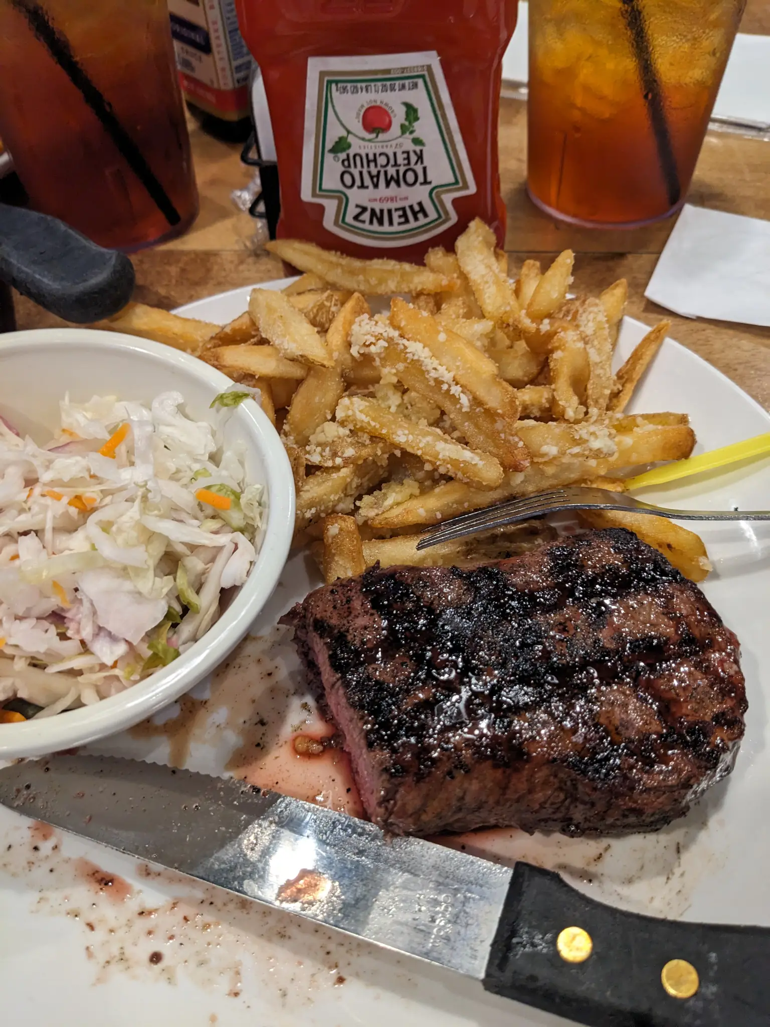 A plate with steak, french fries, and cole slaw.