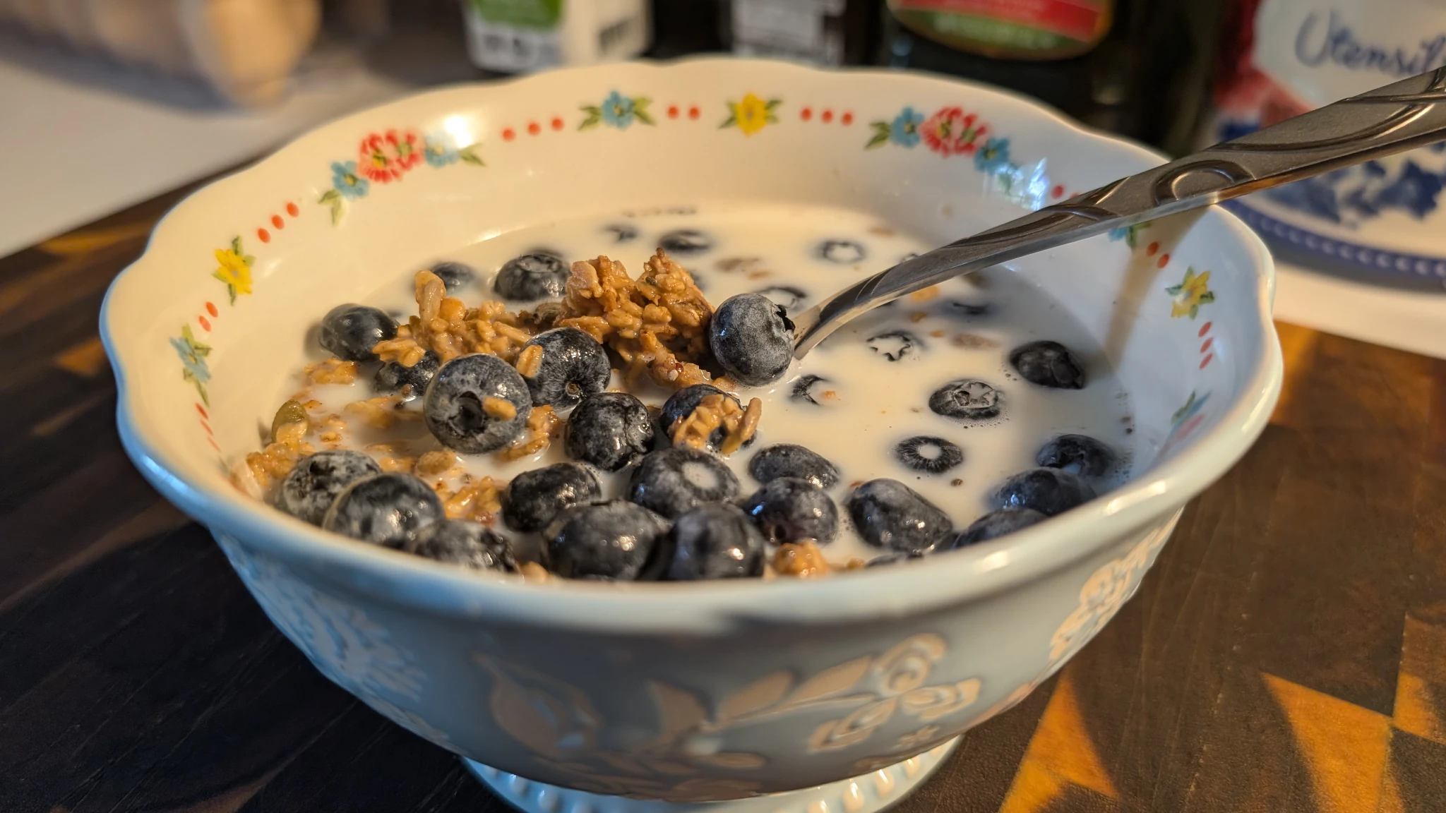 Bowl of granola, topped with blueberries and milk.